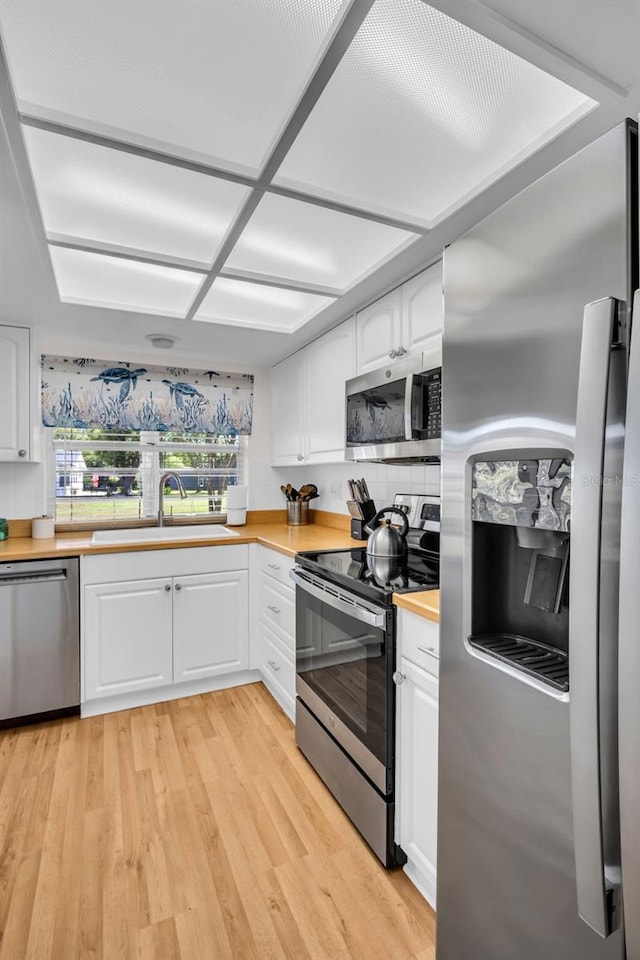1657 Glengarry Dr, Palm Harbor, FL 34684 - kitchen featuring stainless steel appliances, white cabinetry, a sink, and light wood-type flooring