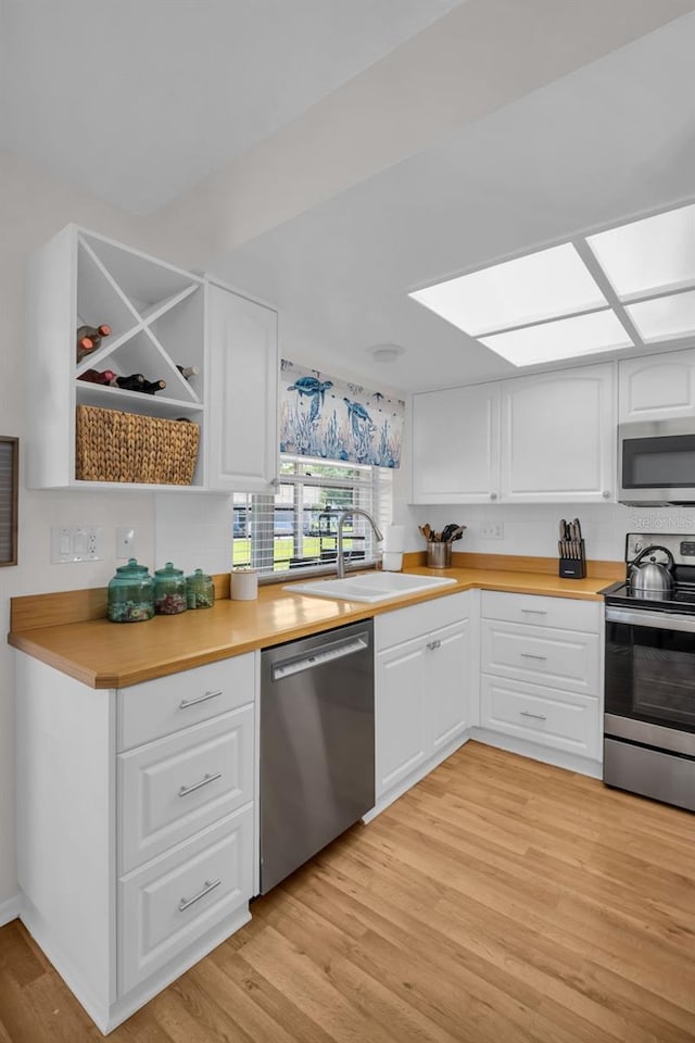 1657 Glengarry Dr, Palm Harbor, FL 34684 - kitchen featuring light wood-type flooring, light countertops, white cabinets, a sink, and stainless steel appliances