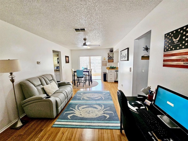 1657 Glengarry Dr, Palm Harbor, FL 34684 - living room featuring a textured ceiling, a ceiling fan, baseboards, wood finished floors, and visible vents