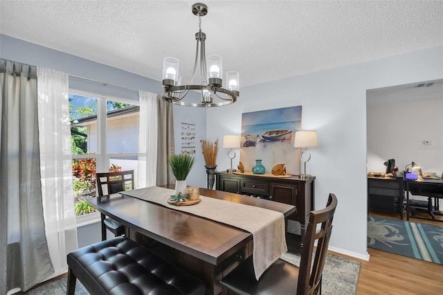1657 Glengarry Dr, Palm Harbor, FL 34684 - dining room featuring baseboards, a textured ceiling, a chandelier, and light wood-style flooring