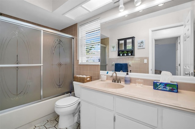 1657 Glengarry Dr, Palm Harbor, FL 34684 - bathroom with tile walls, bath / shower combo with glass door, vanity, tile patterned floors, and toilet