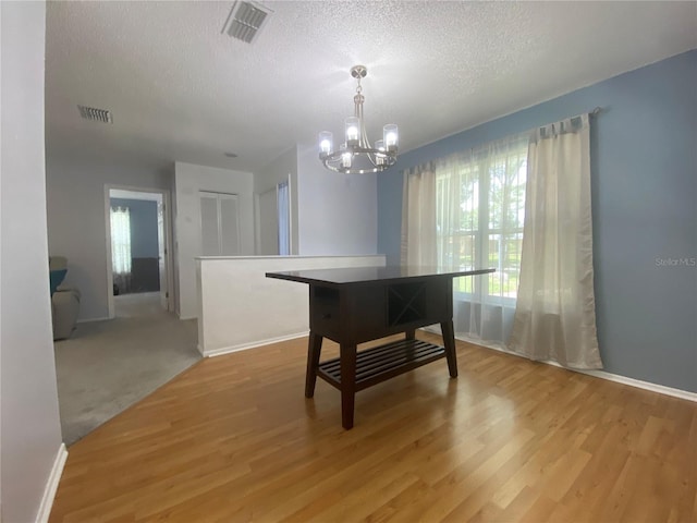 1657 Glengarry Dr, Palm Harbor, FL 34684 - dining area featuring a chandelier, a textured ceiling, and light wood-style floors