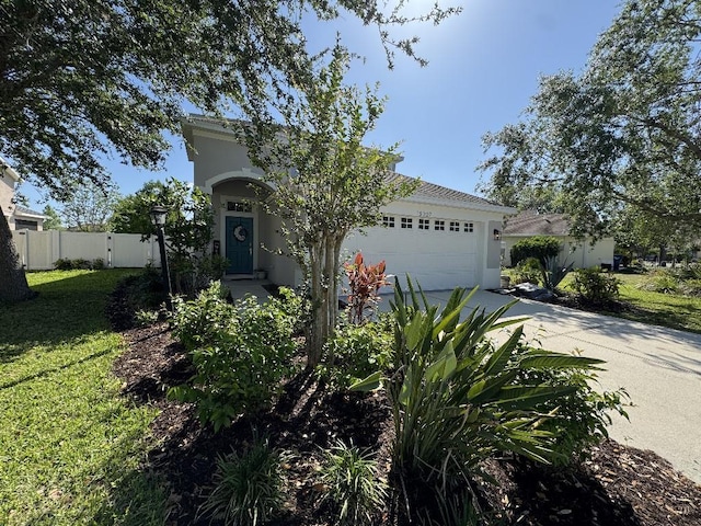 view of front of property with stucco siding, a front yard, fence, an attached garage, and driveway