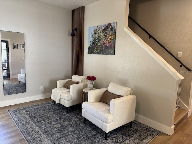 sitting room with baseboards, stairway, and wood finished floors