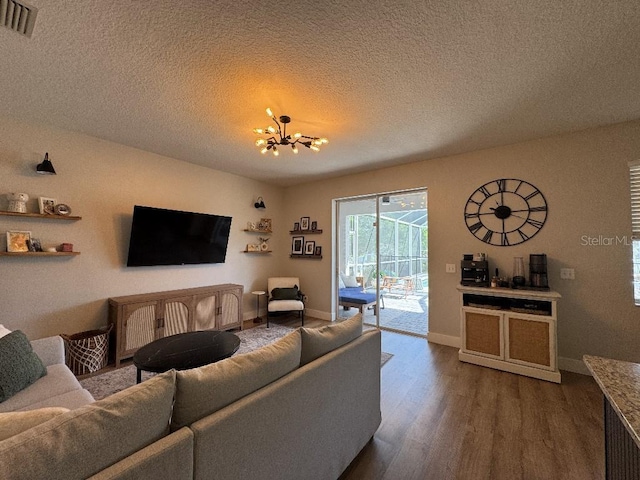 living area with visible vents, baseboards, a chandelier, a textured ceiling, and dark wood finished floors