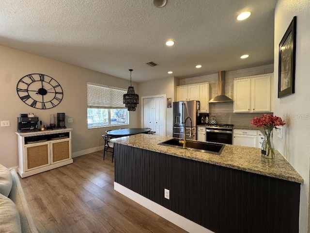 kitchen featuring appliances with stainless steel finishes, wall chimney range hood, white cabinetry, and visible vents