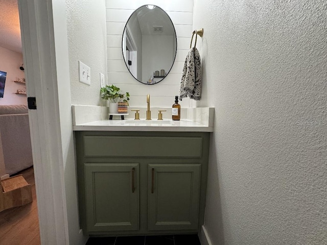 bathroom featuring a textured wall, vanity, and wood finished floors