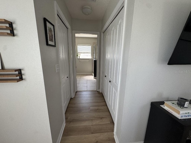hallway featuring baseboards and wood finished floors