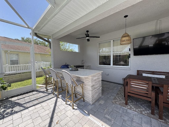 view of patio featuring outdoor dining area, glass enclosure, outdoor dry bar, and ceiling fan