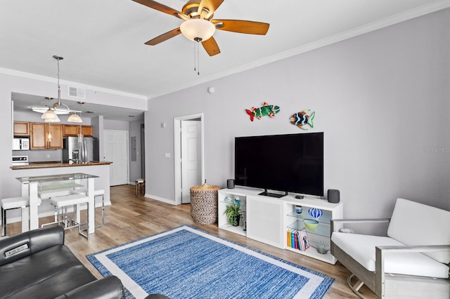 living room featuring light wood-type flooring, ceiling fan, ornamental molding, and visible vents