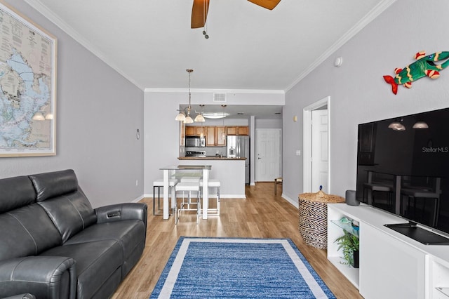 living area featuring ornamental molding, light wood finished floors, visible vents, and a ceiling fan