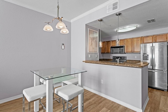 kitchen featuring black microwave, visible vents, wood finished floors, and stainless steel fridge