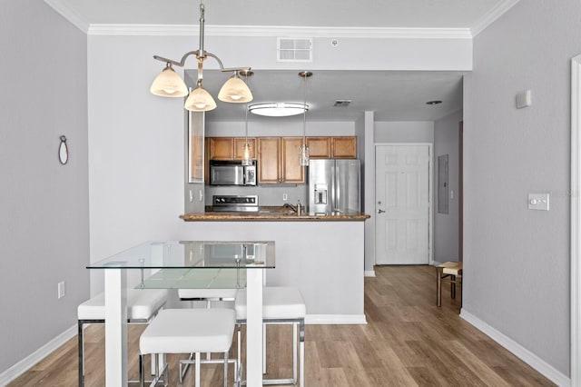 kitchen with crown molding, visible vents, wood finished floors, and stainless steel appliances