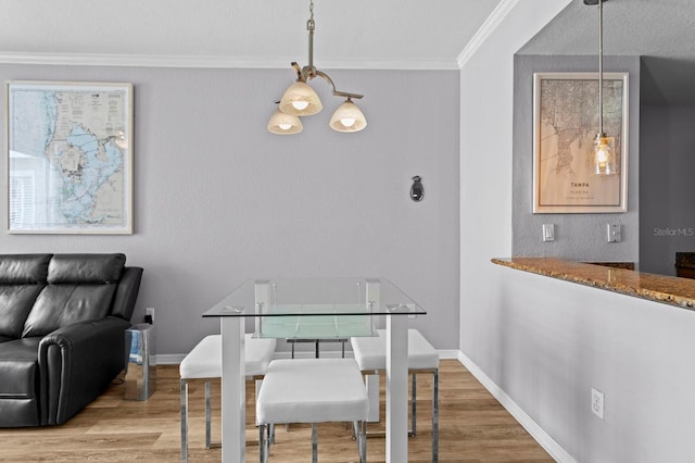 dining space with ornamental molding, baseboards, and wood finished floors