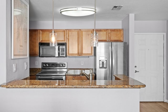kitchen with visible vents, decorative light fixtures, dark stone counters, and stainless steel appliances