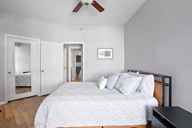 bedroom with wood finished floors, a ceiling fan, and visible vents