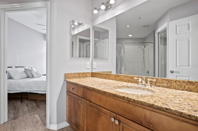 bathroom featuring a shower with shower curtain, ensuite bath, vanity, and wood finished floors
