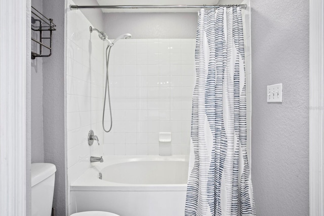 bathroom featuring a textured wall, shower / bath combination with curtain, and toilet