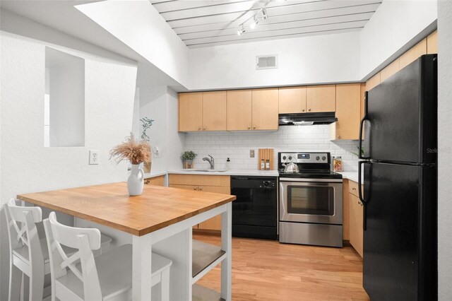 2410 W Azeele St Unit 228, Tampa, FL 33609 - kitchen with black appliances, light brown cabinetry, under cabinet range hood, light wood-type flooring, and wooden counters