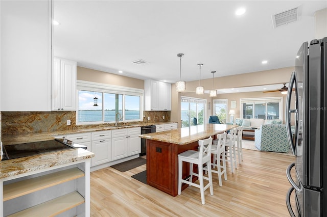 9048 Wharf Ave, Placida, FL 33946 - kitchen with visible vents, dishwasher, freestanding refrigerator, light wood-style floors, and light stone counters