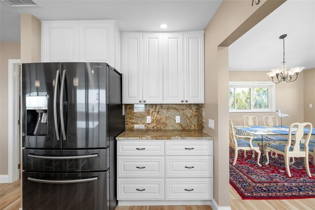 9048 Wharf Ave, Placida, FL 33946 - kitchen with light wood finished floors, refrigerator with ice dispenser, a notable chandelier, and light stone countertops
