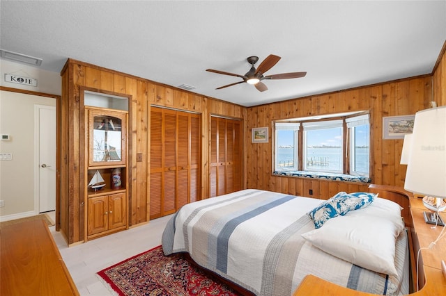 9048 Wharf Ave, Placida, FL 33946 - bedroom featuring ceiling fan, ornamental molding, visible vents, wood walls, and multiple closets