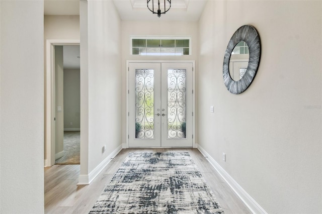 foyer with light wood-type flooring, french doors, and baseboards