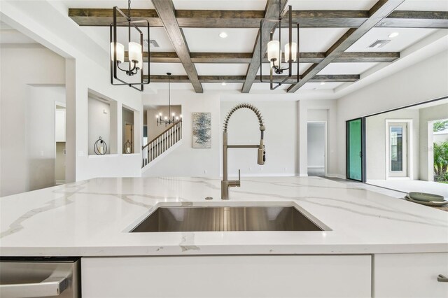 kitchen featuring open floor plan, a sink, an inviting chandelier, and coffered ceiling