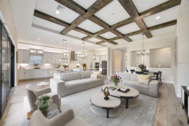 living room with visible vents, an inviting chandelier, light wood-style floors, and beamed ceiling
