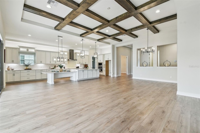 living room with an inviting chandelier, beamed ceiling, light wood-style flooring, coffered ceiling, and baseboards