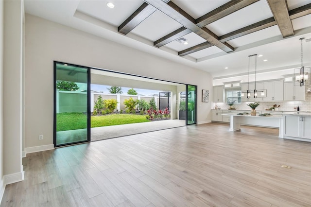 living room featuring beamed ceiling, baseboards, an inviting chandelier, and coffered ceiling