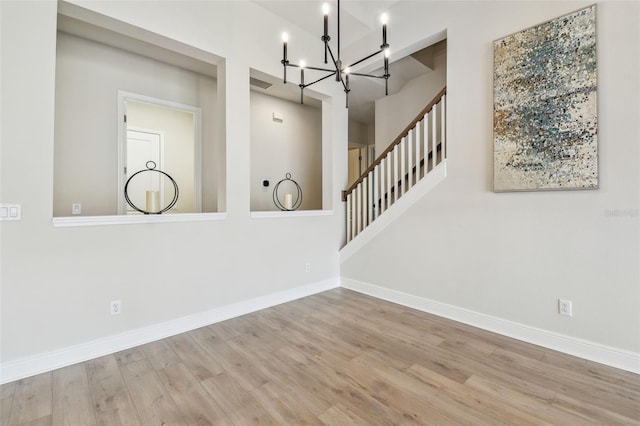 interior space with a notable chandelier, baseboards, a high ceiling, and wood finished floors