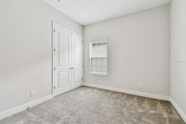 unfurnished bedroom featuring a closet, baseboards, and carpet