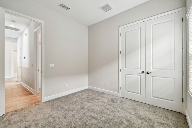 unfurnished bedroom featuring a closet, visible vents, baseboards, and carpet