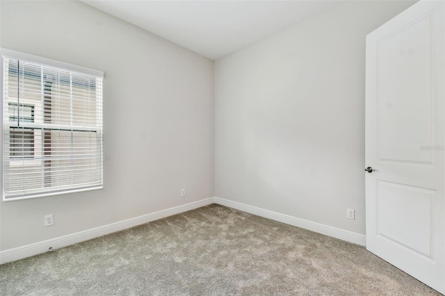 carpeted spare room featuring baseboards and plenty of natural light