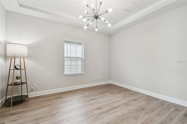 spare room with a notable chandelier, light wood-style flooring, crown molding, visible vents, and a raised ceiling