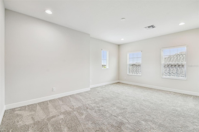 carpeted empty room featuring visible vents, baseboards, and plenty of natural light