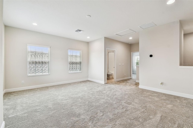 empty room with plenty of natural light, visible vents, and light colored carpet