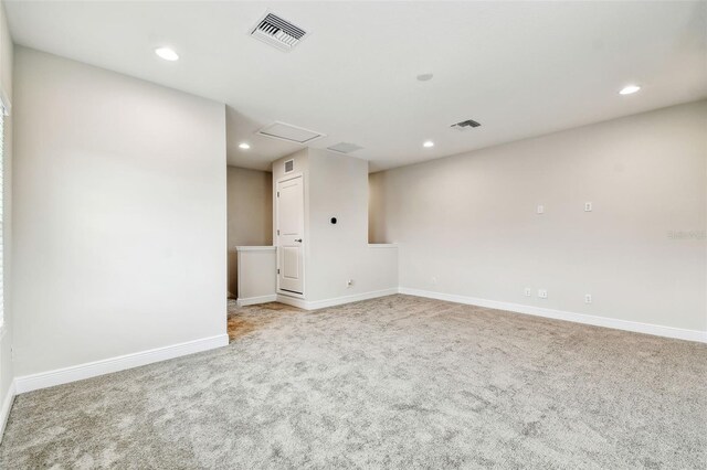 carpeted empty room with visible vents, baseboards, recessed lighting, and attic access