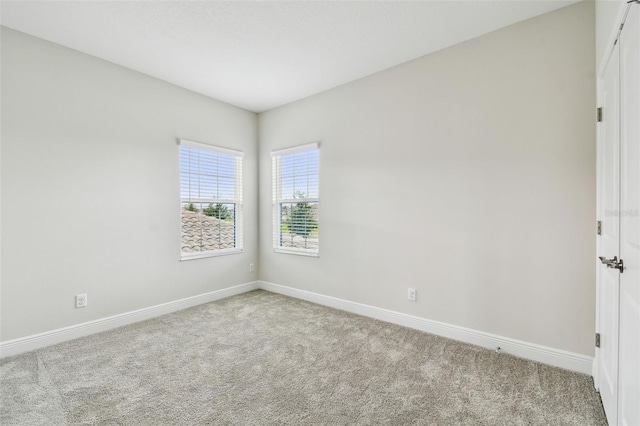 carpeted empty room featuring baseboards