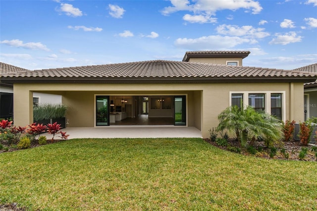 back of property featuring a yard, a tiled roof, a patio area, and stucco siding