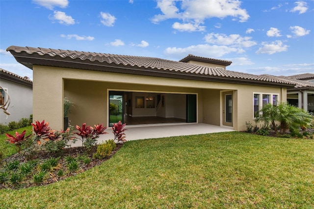 back of property with a yard, a tile roof, a patio area, and stucco siding