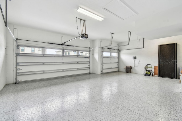 garage with a garage door opener and concrete block wall