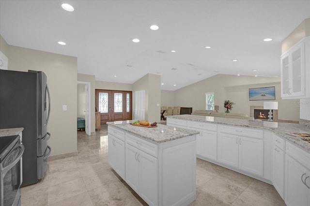 3506 Seaway Dr, New Port Richey, FL 34652 - kitchen with glass insert cabinets, appliances with stainless steel finishes, vaulted ceiling, light stone countertops, and a kitchen island