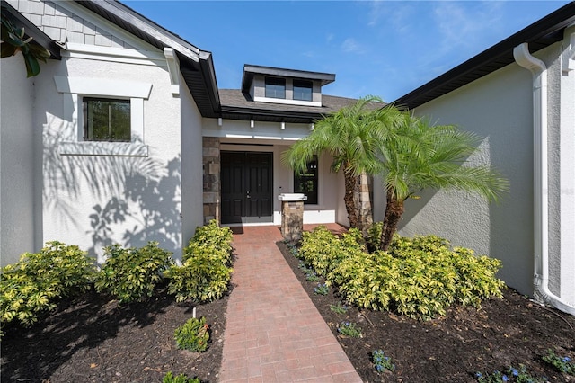 property entrance featuring a porch, stone siding, and stucco siding