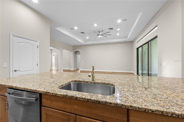 kitchen with a sink, ceiling fan, a tray ceiling, arched walkways, and dishwasher