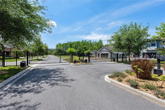 view of road featuring curbs, a gated entry, and a gate