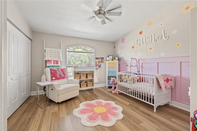 14910 Par Club Cir, Tampa, FL 33618 - bedroom featuring a closet, a nursery area, a ceiling fan, wood finished floors, and a wainscoted wall