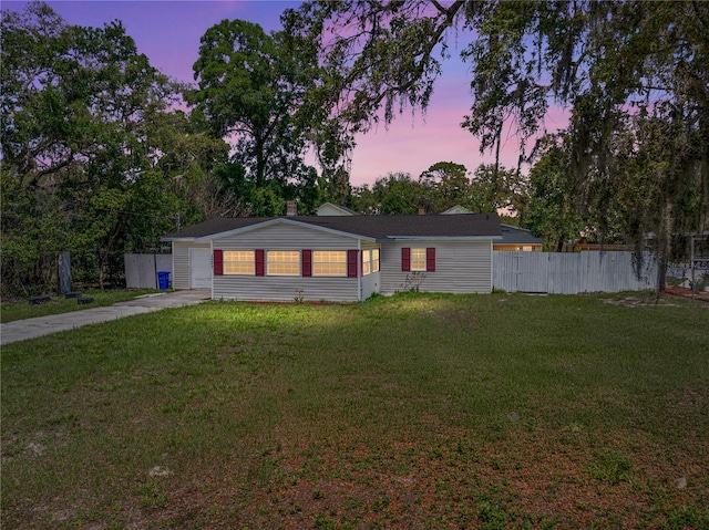 view of front of property with an attached garage, driveway, fence, and a lawn