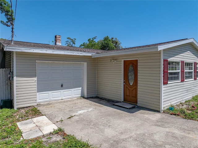 single story home with an attached garage, a shingled roof, and concrete driveway